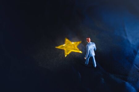 Success in Business or Talent Concept. Top View of a Miniature Businessman Standing on a Yellow Golden Starの写真素材