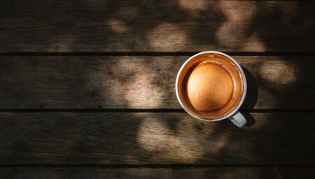 Hot Coffee Latte Cup on Wooden Table under with Natural Light. Top View. Relaxing under the Treeの写真素材