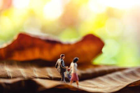 Love and Happy Family. Work Life Balance Concept. Miniature of Father, Mother and Son holding Hands and Walking on Dry Leaf in Parkの写真素材