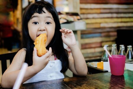 Soft Focus of a 4-5 Years Old Child Eating Food in a Restaurant. Playful Girl. Looking at Cameraの写真素材