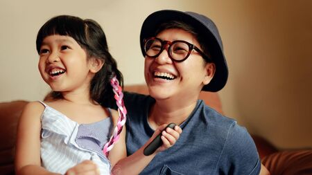Happy Person, a Cute Girl Smiling sitting on Sofa with Her Parent. Happiness Moment by a Big Teeth Smile, Enjoying Somethingの写真素材