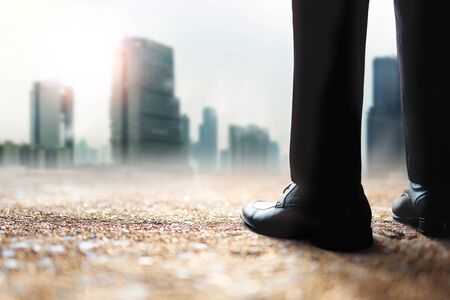 Challenging of Business Company to Helping World Environment and Global Warming Issue. Low Section of Businessman Standing to Looking at Urban Building in Haze Hot Lightの写真素材