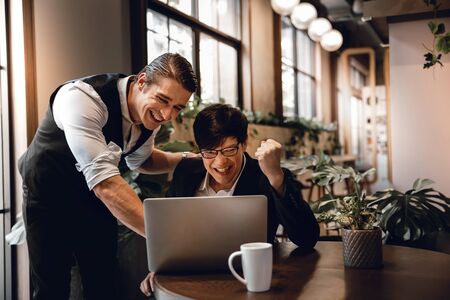 Teamwork or Working Together Concept. Two Businessman Working on Laptop in Creative Working Space. Work Partner Glad for Project Successの写真素材