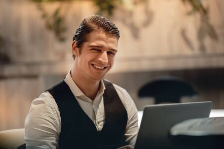 Smiling Businessman Working on Computer Laptop in Creative Working Space or Cafe. Headshot, Looking...