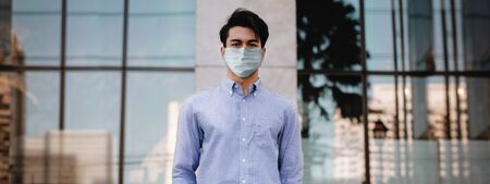 Covid-19 Situation in Business Concept. Businessman with Surgical Mask standing in the City. Protected and Care of Health. Stressed out due to Corona Virus. Looking at Cameraの写真素材