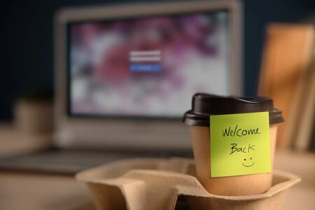 Back to Work Concept. Closeup of Welcome Note on Takeaway Coffee Cup in Office Desk. Message from a Colleague or Bossの写真素材