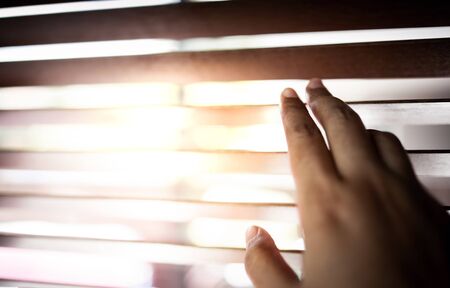 Hand Opening Sunblind inside the  House. Sunlight Through the Window