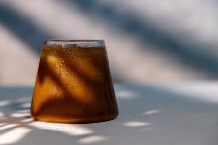 a Glass of Ice Coffee. Cold Drink in a hot Summer Day. Sunlight shading on the Wall
