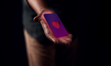Red Heart Card on Hand. Giving a Donate Concept. Young Man Offering a Helping Hand. Cropped and Selective Focusの写真素材