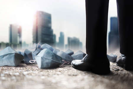 Challenging of Company in Covid-19 Situation Concept. Impact from Coronavirus. Crash and Down Crisis in Business and Finance. Businessman Standing  in City. Many Surgical Mask on the Groundの写真素材