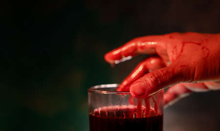 Halloween Concept. Bloody Hand on a Glass of Red Blood. Horror Night. Vampire who Drinking Fresh Bloodの写真素材