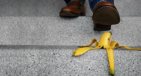 Accident in Daily Life Concept. Man Stepping Down Stair on a Banana Peel. Insurance or Business Metaphorの写真素材