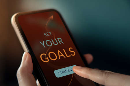 Goals and Strategy Concept. Hand Making a Personal Goal via Mobile Phone application. Closeup shotの写真素材