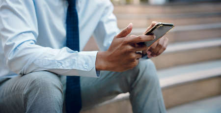 a Businessman Using Mobile Phone in the City. Cropped image, selective focus on Smartphoneの写真素材