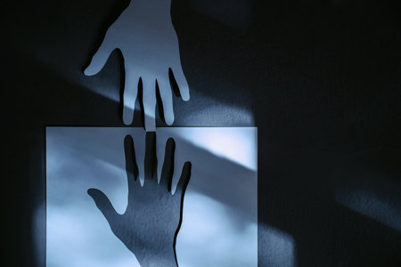 Help, Care, Support or Partnership Concept. Paper Cut as Hands Shape hanging on the wall. look like the top one trying to help the one below. Touching each otherの写真素材
