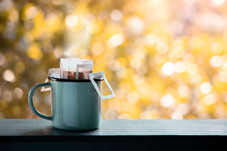 Dripping Coffee Outdoor in the Morning. Making Hot Drink by Instant Coffee Drip Bag. Cozy Living Lifestyleの写真素材
