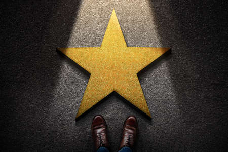 Success in Business or Personal Talent Concept. Top View of Business Person in Working Shoes Standing in front of a Golden Star. Light Shining on the Dark Cement Floorの写真素材