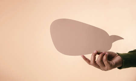 Blank Speech Bubble Mockup Image. Hand Holding an Empty Paper Speech to Saying or Expressing a...