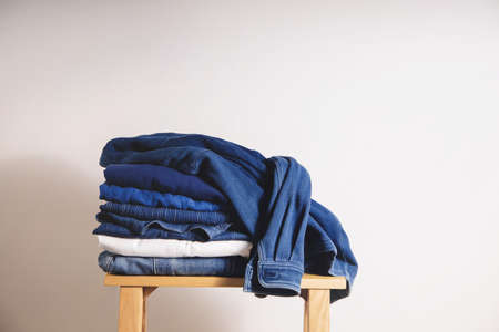 Clothes Concept. Stack of Clothing on Wooden bench by the Whaite Wall. Blue Navy Toneの写真素材