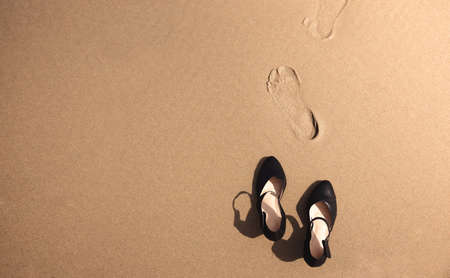 Work Life Balance Concept. Business Woman take off her Working Shoes and leave it on the Sand Beach for Walk into the Sea on Sunny Day. Quit a Job, Office Outing or Summer Vacation. Top Viewの写真素材