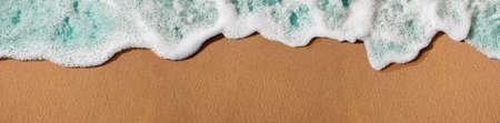 Empty Sand Beach and Soft Blue Wave on Summer Sunny Day. Natural Texture Background. Wide and Long Size for Copy Space. Top View. Focus on Sandの写真素材