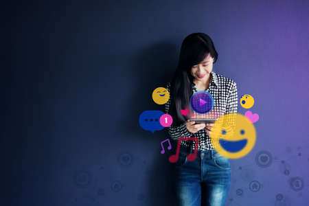 Woman Enjoying while using Social Media application via Mobile Phone. Lifestyle of Modern Female. surrounded by many iconsの写真素材