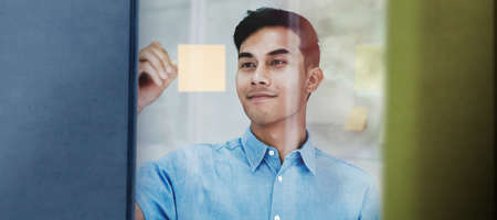 Young Asian Businessman Working in a Meeting Room. Smiling and Concentrate on Document Note on Board