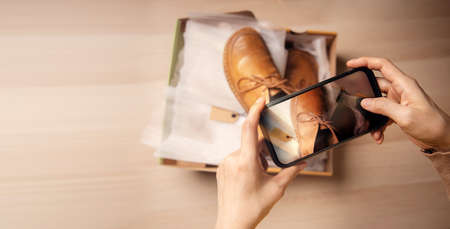 Customer Experiences Concepts. Customer Unboxing and Taking Photo of her New Shoes for Review, Feedback and Satisfaction. Using Mobile Phone to Selling Online Productsの写真素材