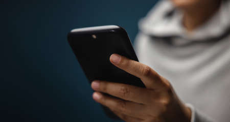 Closeup of Hand Using Mobile Phone. Cropped image. Selective Focus. Using Technology for Communication in Real Lifeの写真素材