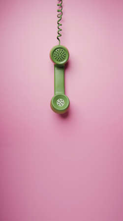 Green Vintage Retro Telephone Handset Hanfing on Pink background. Old Object from 1980-1990, Technology and Communication in the Past. Clean, Colourful  and Minimalの写真素材