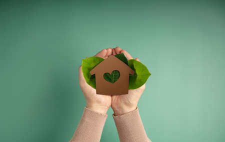 Eco House, Carbon Neutral Concepts. Clean Energy. Green Power. Hands Holding a Craft Papaer House...
