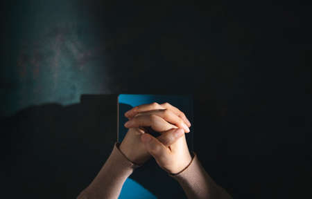 Spirituality, Religion and Hope Concept. Person Praying by Holy Bible on Desk. Symbol of Humility,...