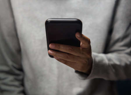 Closeup of Hand Using Mobile Phone. Cropped image. Selective Focus. Using Smartphone for Communication, Texting, Reading or Playing Gameの写真素材