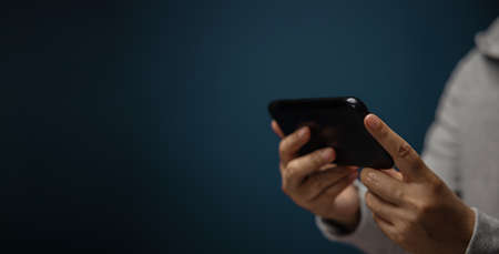Closeup of Hand Using Mobile Phone. Cropped image. Selective Focus. Using Smartphone for Communication, Texting, Reading or Playing Gameの写真素材
