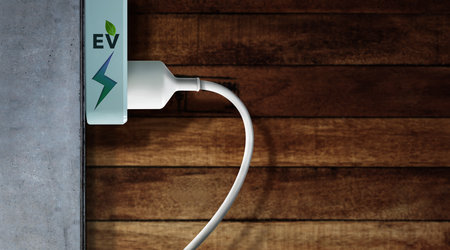 Clean Energy Concept. Close-up of EV Power Socket on the Wall. Green leaf and Thunderbolt Icon print...