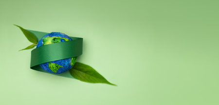 World Earth Day Concept. Plant a Tree on the Planet, ESG, Renewable and Sustainable Resources. Environmental Care. Green Ribbon and Leaf Embracing a Globe. Top Viewの写真素材