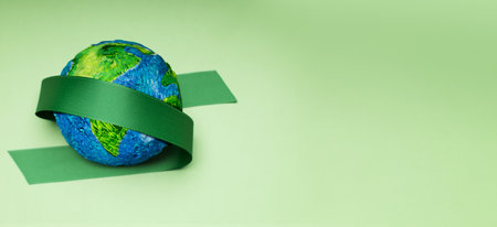World Earth Day Concept. Green Energy, ESG, Renewable and Sustainable Resources. Environmental Care. Green Ribbon Embracing a Globe. Top Viewの写真素材