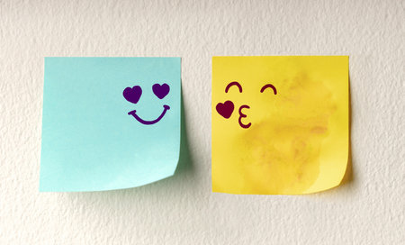 Couple in Love Concept. Two Sticky Notes on the white Wall with Cute Hand Drawn Emoticon Face as...