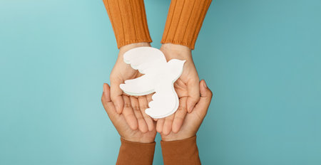 Hands gently holding a white dove symbolizing peace, Freedom, harmony, human rights, and anti-violence valuesの写真素材