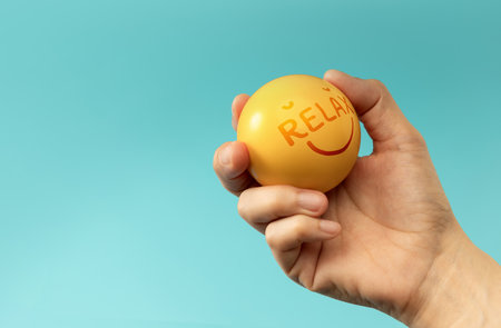 Hand holding Stress ball labeled Relax used for emotional control and mental health practice, helping reduce tension and improve mood.の写真素材