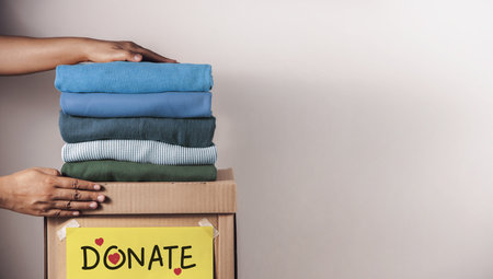 Clothes Donation, Renewable Concept.Hands folding and packing clothes into box at home, representing kindness, donation, minimalism, and social responsibilityの写真素材