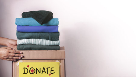 Clothes Donation, Renewable Concept.Hands folding and packing clothes into box at home, representing kindness, donation, minimalism, and social responsibilityの写真素材