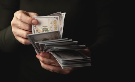 Hands counting US dollar banknote, symbolizing finance, payment, banking, and economic transactions. Closeup Front viewの写真素材