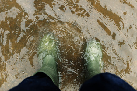 POV shot of person with Rain Boots standing in Floodwater. Flooding, climate change, and...
