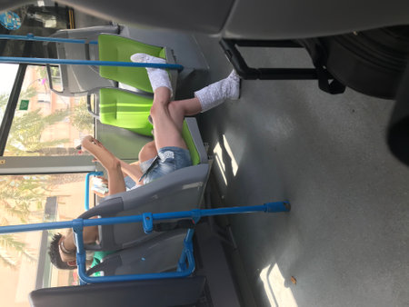 Young woman is sitting on the bus and looking out the window.の写真素材