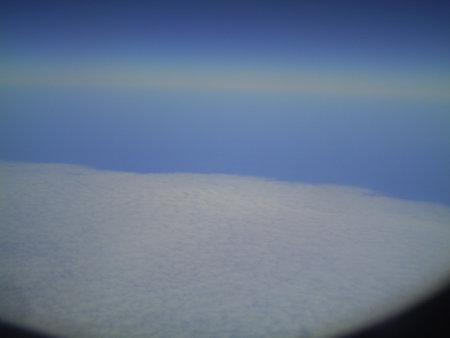 Clouds in the blue sky as seen through window of an aircraftの写真素材