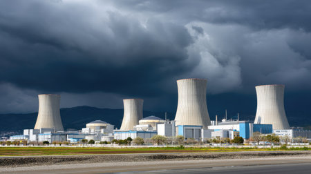 A modern industrial nuclear power plant featuring prominent cooling towers set against a dramatic cloudy sky, showcasing energy generation and technological advancement.の素材