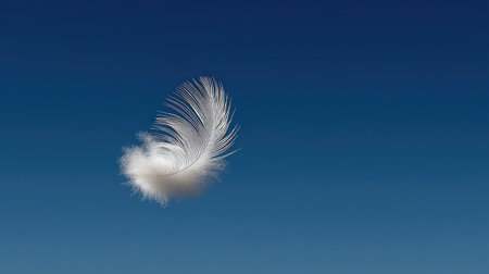 A delicate white feather gracefully floats against a deep blue sky, symbolizing tranquility and freedom, perfect for conveying a sense of peace and lightness.の素材