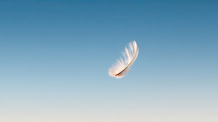 A delicate feather floats gracefully against a clear blue sky, symbolizing freedom and tranquility. The soft texture and simple beauty evoke a serene moment in nature.の素材