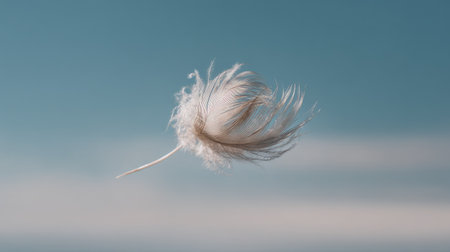 A delicate feather floats gracefully against a clear blue sky, symbolizing freedom and tranquility in nature. The soft texture and minimalism create a serene atmosphere.の素材